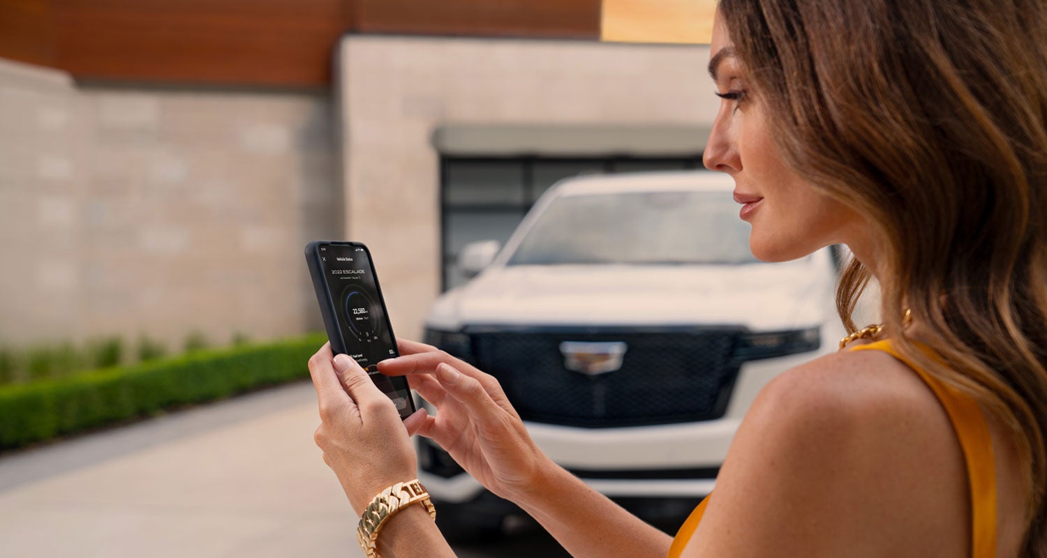 lady checking her mobile with a Cadillac vehicle background | Sarant Cadillac in Farmingdale NY